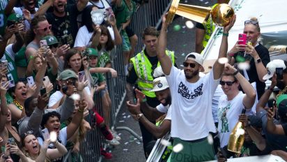 Getty Images - Boston, MA - June 21: Boston Celtics forward Jayson Tatum holds up the Larry O'Brien championship trophy. Overhead view of the parade route along Tremont street during a duck boat parade to celebrate the 18th Boston Celtics NBA championship. (Photo by Barry Chin/The Boston Globe via Getty Images)