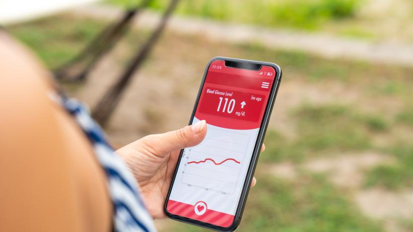 Woman wearing a glucose sensor checking her blood sugar level using a smartphone app. Tottori, Japan