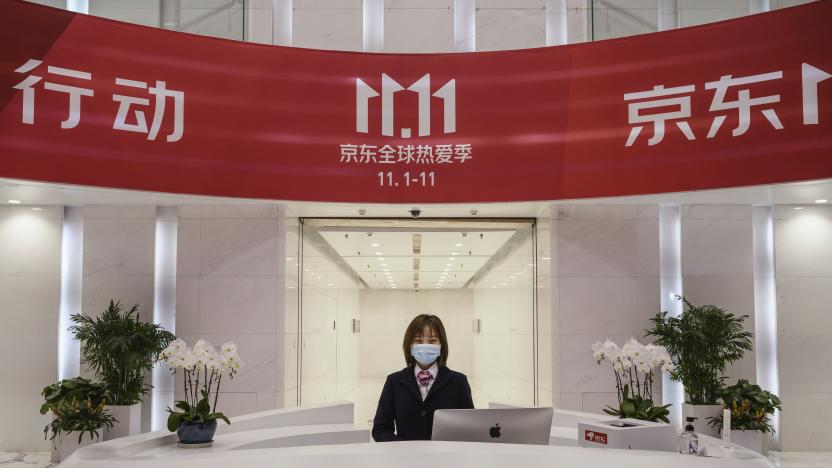 BEIJING, CHINA - NOVEMBER 11: A receptionist from Chinese e-commerce giant JD.com poses from her desk under the Singles Day banner in the lobby at the company's headquarters during an organized tour on November 11, 2020 in Beijing, China. The online shopping blitz, known as Singles Day or Double 11, is the world's largest retail event and comes as Chinese consumers are emerging from the COVID-19 pandemic. The revival of consumer consumption is expected to boost China's economy, which is already showing signs of post-pandemic recovery and providing a bright spot for global brands and retailers. Singles Day sales for China's biggest e-commerce giants like JD.com are on pace to break previous records, pulling in $56 billion U.S. in the first 30 minutes, when combined with three days of pre-event sales. (Photo by Kevin Frayer/Getty Images)