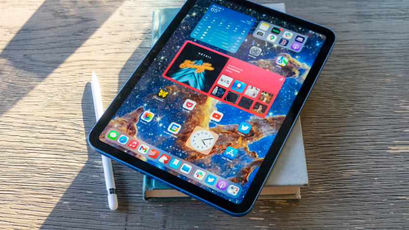 An Apple iPad on top of a book on a wooden table.