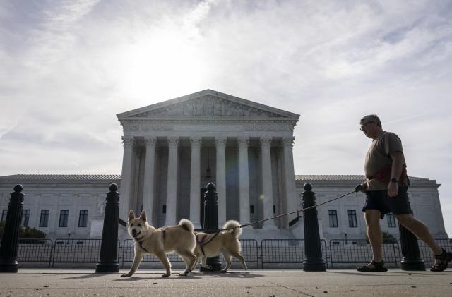 WASHINGTON, DC - JUNE 1: A man walks his dogs past the U.S. Supreme Court on June 1, 2021 in Washington, DC. The Supreme Court is set to issue several rulings this month, including cases concerning the Affordable Care Act, a dispute involving LGBT and religious rights, and a case related to voting restrictions in Arizona. (Photo by Drew Angerer/Getty Images)