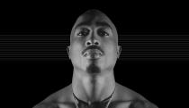 Photo of the late Tupac Shakur, staring down at the camera against a black background with subtle horizontal gray lines.