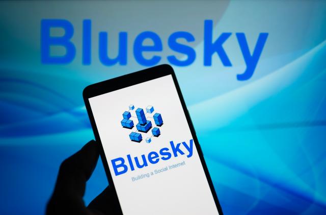 Bluesky logo displayed on a smartphone with Bluesky web page seen in the background, in this photo illustration. On 15 October 2023, in Brussels, Belgium. (Photo illustration by Jonathan Raa/NurPhoto via Getty Images)