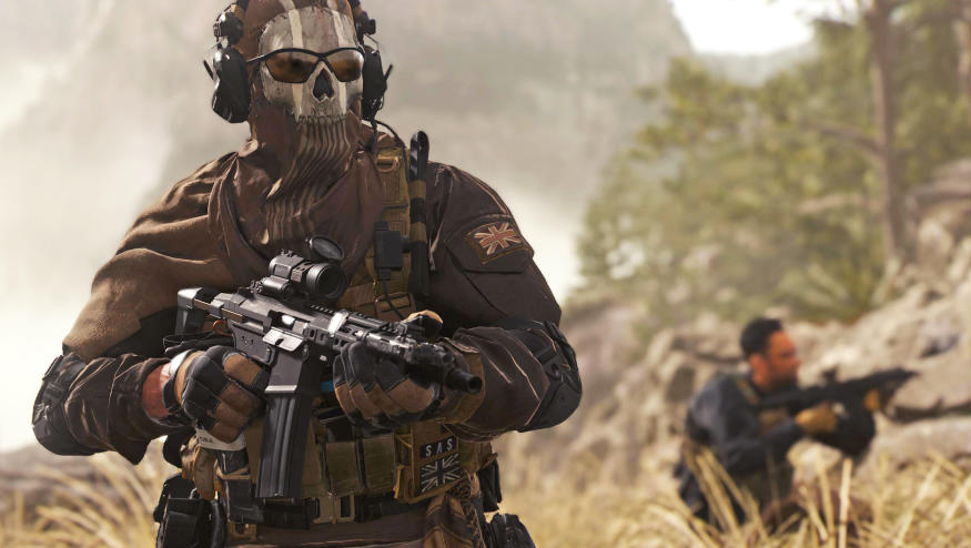 A still image from 'Call of Duty: Modern Warfare 2' showing two soldiers in tall grass. One wears a skull mask and sunglasses as he heads toward the camera with a gun raised.