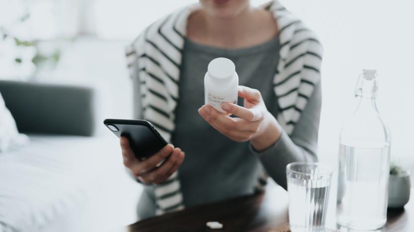 Close up of young Asian woman holding a pill bottle, consulting to her family doctor online in a virtual appointment over the smartphone at home