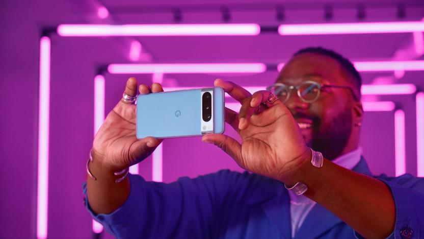 A person takes a photo with a horizontally orientated Google Pixel 8 Pro. Purple light tubes illuminate the background.