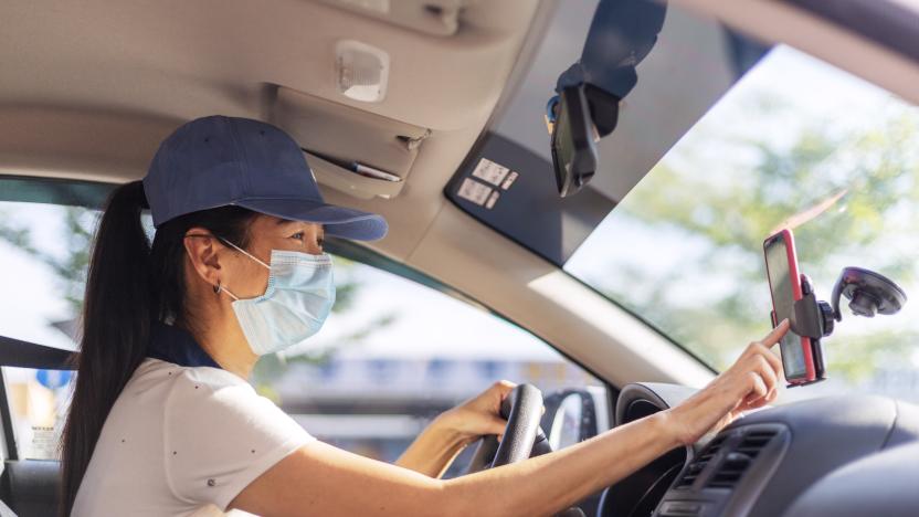 Asian female Car sharing driver checking on the mobilephone searching for job destination, woman wearing face mask while driving