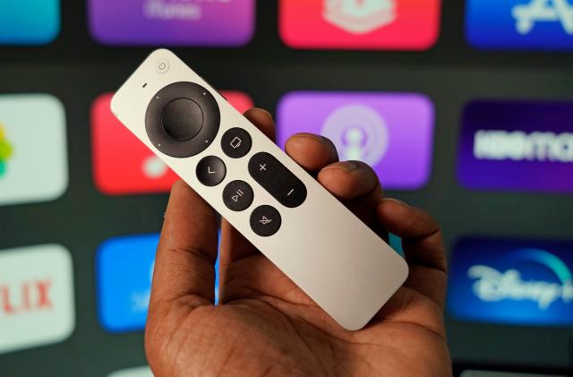 Apple TV remote with a selection of apps in the background