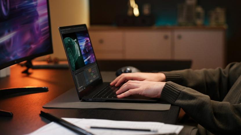 A pair of hands using a laptop on a desk. 