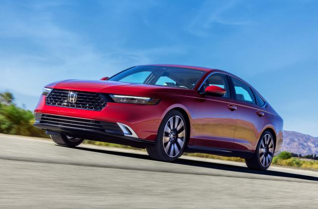 A red Honda Accord driving on flat road under blue skies with hills in the distance