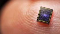 Macro photo of a very small processor on a human finger, where you can see the details of the fingerprint.