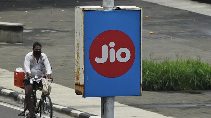 A cyclist passes by an advertising board of Reliance Jio, a digital platform owned by Indian businessman Mukesh Ambani's Reliance Industries, in Mumbai on June 19, 2020. - Ambani said on June 19 that his Reliance conglomerate is net debt free after raising more than $22 billion in a rights issue and selling stakes in its e-commerce unit to Facebook, Saudi Arabia's wealth fund and others. Asia's richest man after upending the Indian telecoms market, Ambani is attempting to do the same in e-commerce with Jio Platforms, taking on US giants Amazon and Walmart in the vast market of 1.3 billion consumers. (Photo by Punit PARANJPE / AFP) (Photo by PUNIT PARANJPE/AFP via Getty Images)