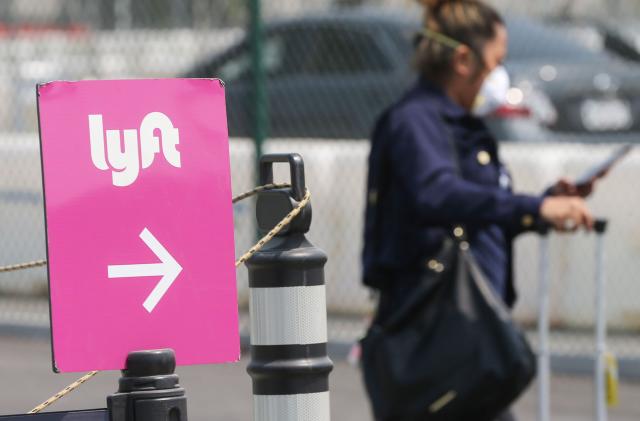 LOS ANGELES, CALIFORNIA - AUGUST 20: An air traveler walks toward a Lyft pickup area at Los Angeles International Airport (LAX) on August 20, 2020 in Los Angeles, California. Uber and Lyft drivers held a rally earlier at the airport calling for basic employment rights. An appeals court granted Lyft and Uber an emergency stay from needing to classify drivers as employees allowing ride-sharing services to continue after a threatened shutdown in California. (Photo by Mario Tama/Getty Images)