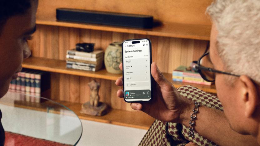 Two people looking at a phone showing Sonos' settings page.