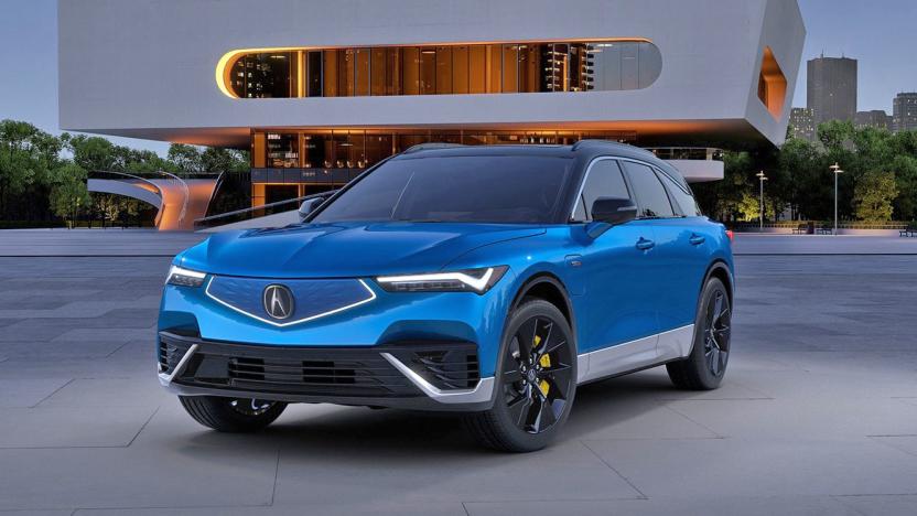Marketing photo of the Acura ZDX electric SUV. The vehicle, in blue trim, sits in front of a modern building.