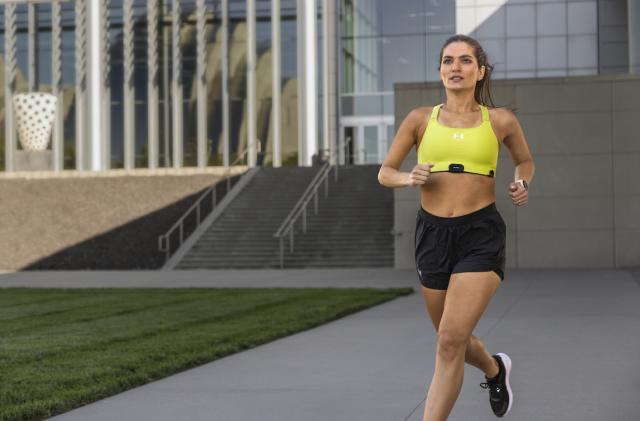 A person runs with the HRM-Fit attached to their sports bra. 