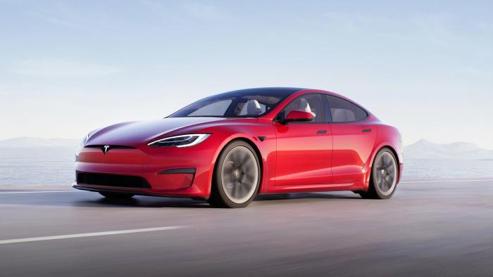 A Tesla Model S Plaid in red races down a coastal highway.