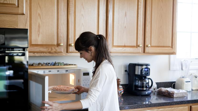 Woman cooking in the kitchen, using microwave