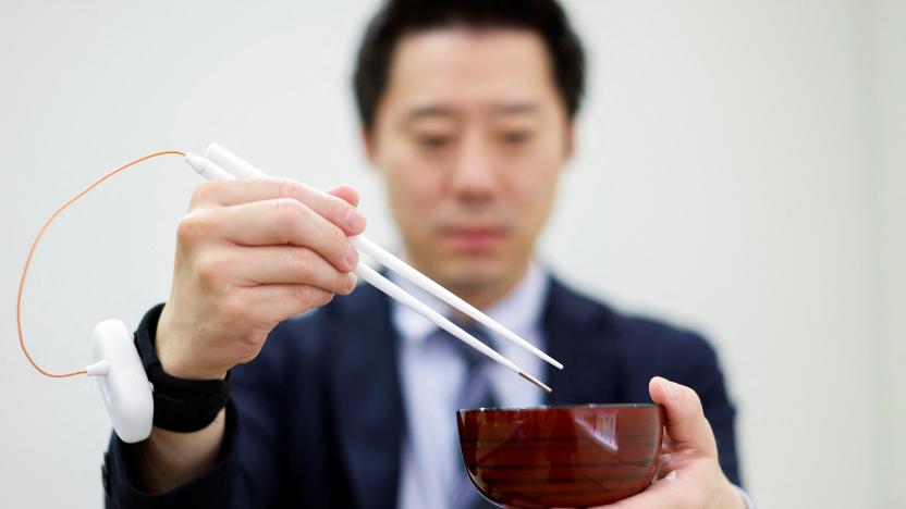 An employee of Kirin Holdings demonstrates chopsticks that can enhance food taste using an electrical stimulation waveform that was jointly developed by the company and Meiji University's School of Science and Technology Professor Homei Miyashita, in Tokyo, Japan April 15, 2022. Picture taken April 15, 2022. REUTERS/Issei Kato