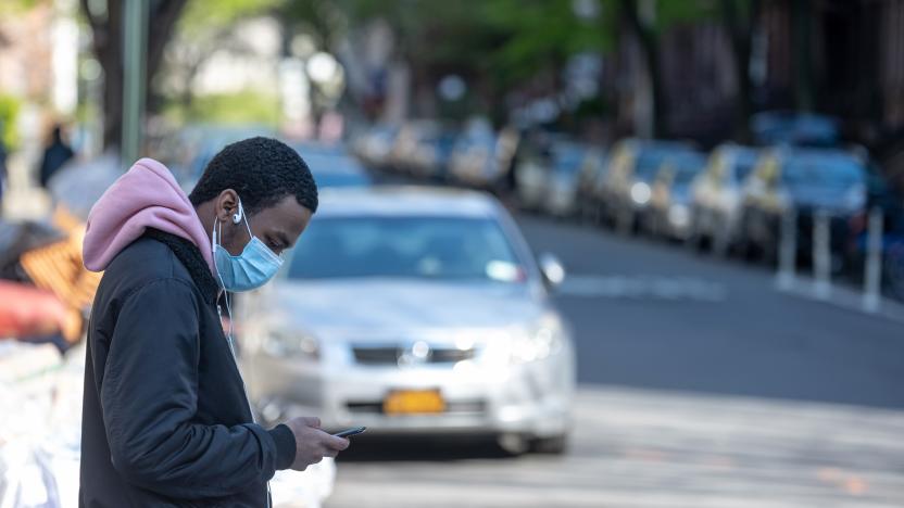 NEW YORK, NEW YORK - APRIL 28: A man wearing a protective mask looks at his iPhone amid the coronavirus pandemic on April 28, 2020 in New York City, New York. COVID-19 has spread to most countries around the world, claiming over 217,000 lives with over 3.1 million cases (Photo by Alexi Rosenfeld/Getty Images)