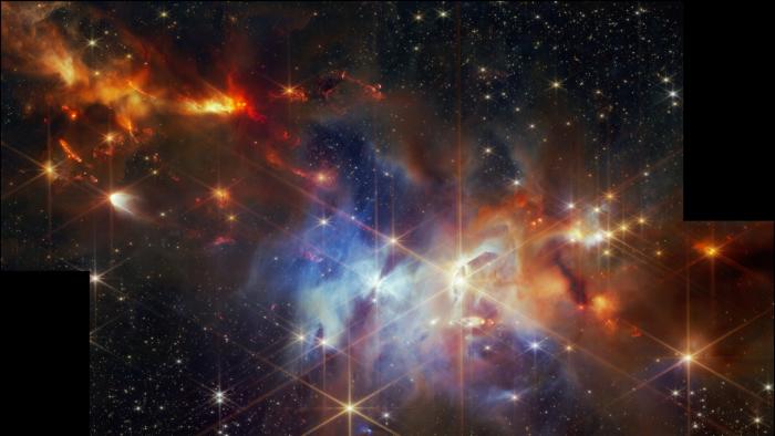 Space image, showing forming stars in the Serpens Nebula. Red, orange, blue, black, diffraction spikes.