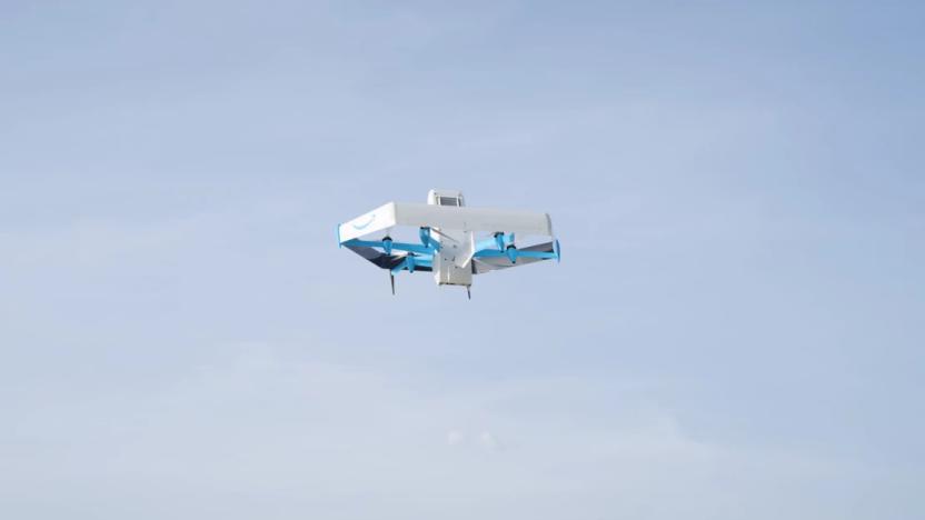 Amazon marketing photo of a Prime Air drone (mostly white with blue accents) flying in the sky. Tops of trees visible below.