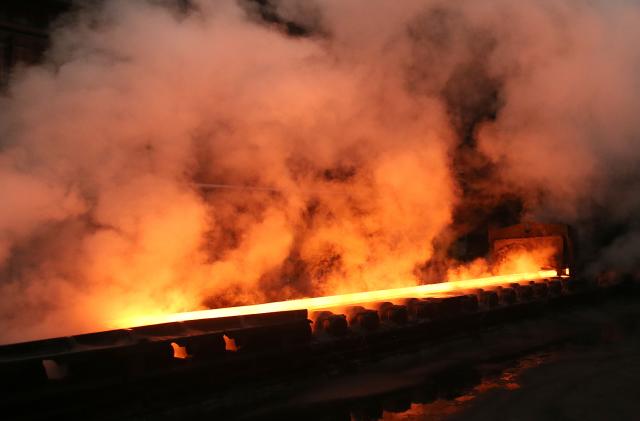 Steam rolls off a slab of steel as it rolls down the line at the Novolipetsk Steel PAO steel mill in Farrell, Pennsylvania, U.S., March 9, 2018. REUTERS/Aaron Josefczyk