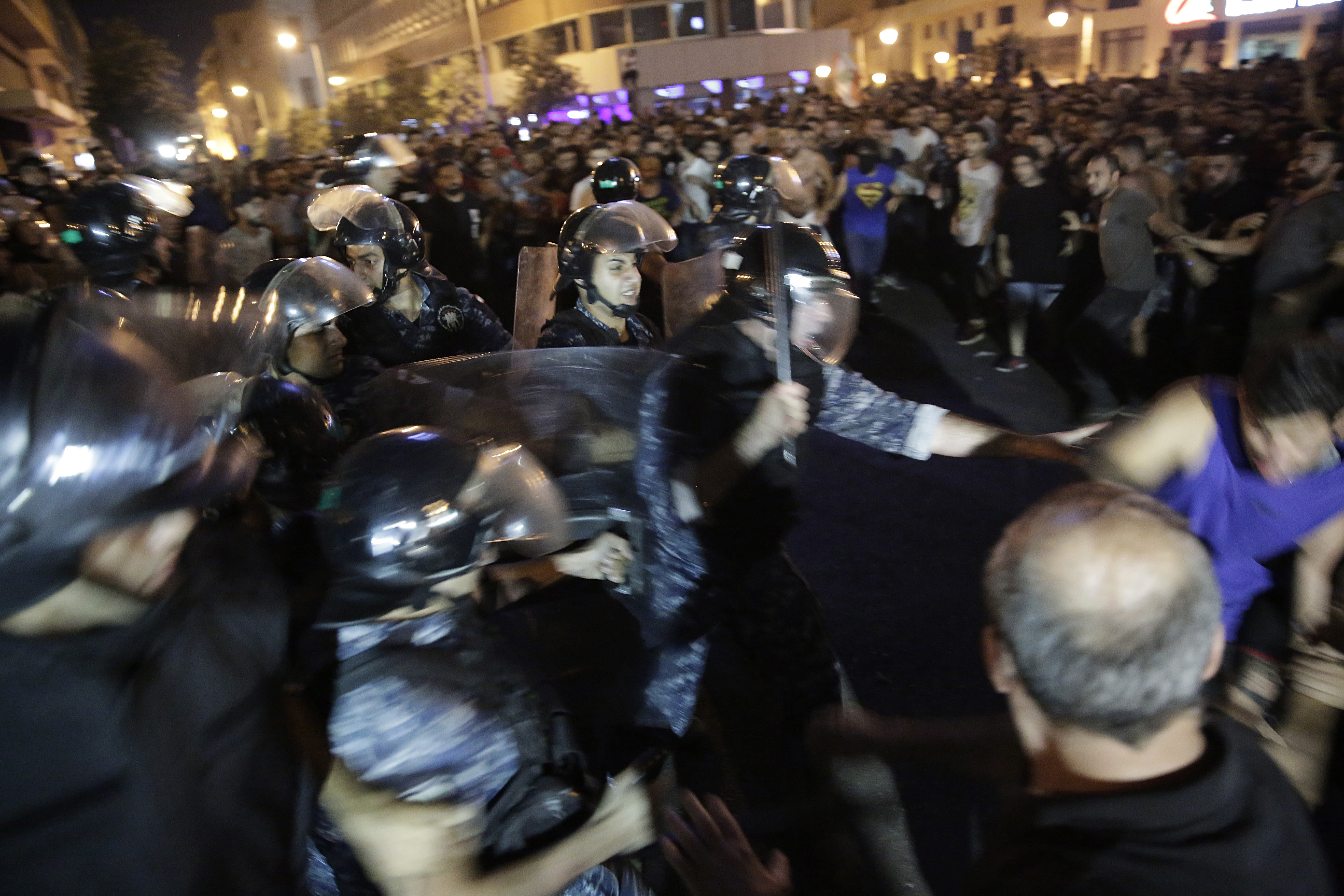 Lebanese anti-government protesters clash with riot policemen on a road in downtown Beirut, Lebanon, Thursday, Oct. 17, 2019. Scores of people are protesting in Beirut and other parts of Lebanon over the government's plans to impose new taxes amid a harsh economic crisis in the country. (AP Photo/Hassan Ammar)