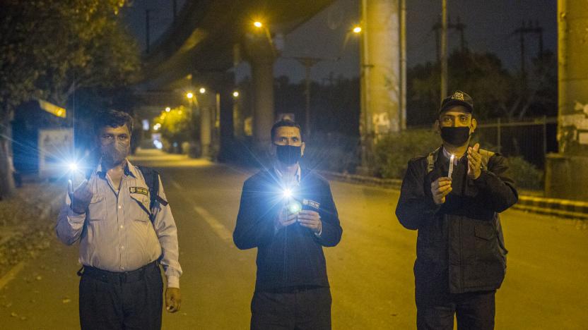 NEW DELHI, INDIA - APRIL 05: Indians hold candles and smartphone flashlights on a deserted main road for nine minutes to show solidarity in the fight against the coronavirus as a nationwide lockdown continues on April 05, 2020 in New Delhi, India. India is under a 21-day lockdown to fight the spread of the virus. After an appeal by Indian Prime Minister Narendra Modi, millions of Indians on Sunday switched off lights in their houses at 9 pm for nine minutes to show solidarity in the country's fight against the coronavirus. The lockdown has already disproportionately hurt marginalized communities due to the loss of livelihood and lack of food, shelter and other basic needs. The lockdown has left tens of thousands of out-of-work migrant workers stranded, with rail and bus services shut down. The closing of state borders has caused disruption in the supply of essential goods, leading to inflation and fear of shortages. There are more than 3,500 positive coronavirus cases in India with currently 99 deaths. (Photo by Yawar Nazir/Getty Images)