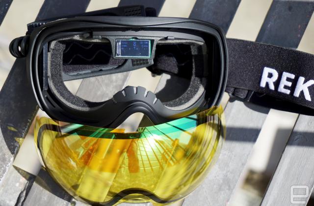 Ski Goggles with yellow lenses that have been removes and a small display in the middle of the frames.                               