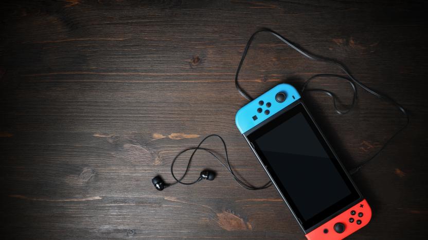 Minsk, Belarus - May 07, 2020: Nintendo Switch game console with black screen and bright joy-con controllers on wood table background. Copy space for text. Top view. Flat lay.