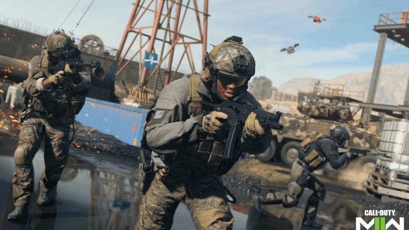 A promo still for the video game 'Call of Duty' showing troops on the ground with weapons up, looking through their sights as they move forward through shallow water in an industrial area.