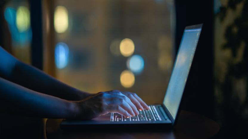 Cropped shot of woman's hand typing on computer keyboard in the dark, working late on laptop at home