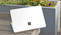 A white device with the Microsoft Windows logo on top of a wooden bench.