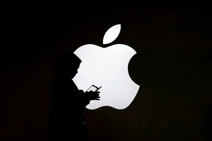 A woman looks at the screen of her mobile phone in front of an Apple logo outside its store in Shanghai, China July 30, 2017. REUTERS/Aly Song     TPX IMAGES OF THE DAY