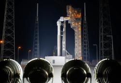 Starliner sitting atop a ULA Atlas V rocket on the launch pad at night