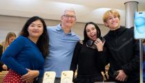 Four people posing behind a table with iPhone displays.