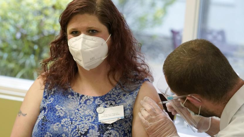 Shylah Hallam-Noel left, a worker at Queen Anne Healthcare, a skilled nursing and rehabilitation facility in Seattle, receives the second shot of the Pfizer vaccination for COVID-19, Friday, Jan. 8, 2021, from a Walgreens Pharmacist, right. The facility had an outbreak of COVID-19 in May of 2020 that resulted in more than 100 positive cases among staff and residents, including Allen, and the deaths of 20 residents and two staff members. (AP Photo/Ted S. Warren)