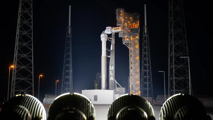 Starliner sitting atop a ULA Atlas V rocket on the launch pad at night