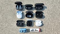 A selection of wireless earbuds sit organized in rows on a granite background.