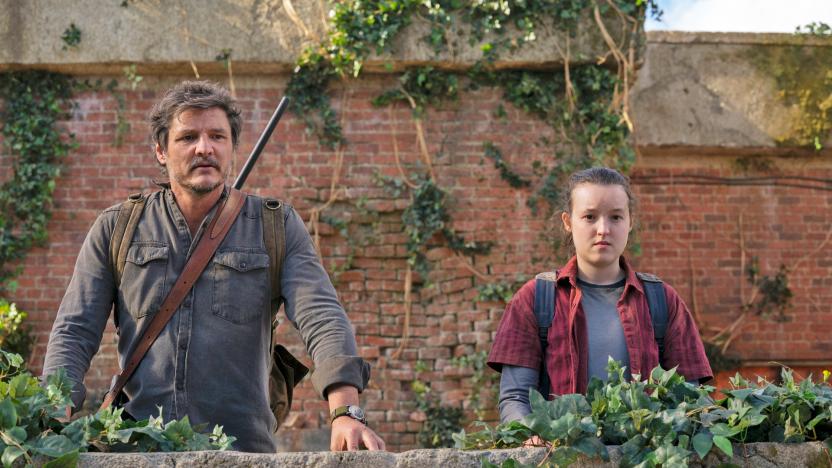 Pedro Pascal and Bella Ramsey stand behind a short brick wall and look at the camera in this promotional image from the TV series 'The Last of Us'.