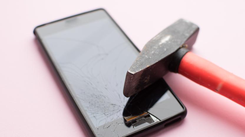 Hammer and mobile phone with broken display on pink background. Crashed smartphone concept.