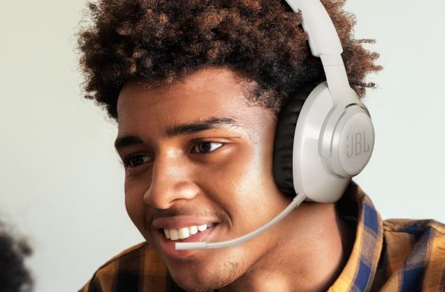 A young man smiling while wearing a JBL gaming headset