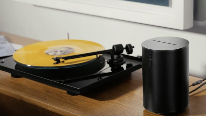 Sonos Era 100 in black on a wooden shelf next to a turntable