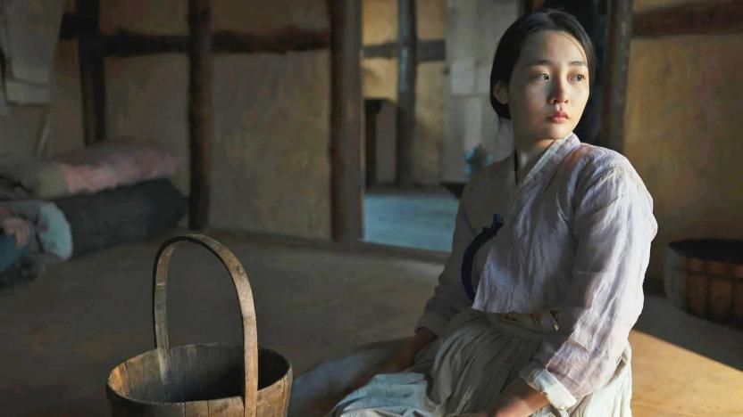 A still from the AppleTV+ historical drama 'Pachinko' showing a young Japanese woman in an austere room next to a wooden bucket.