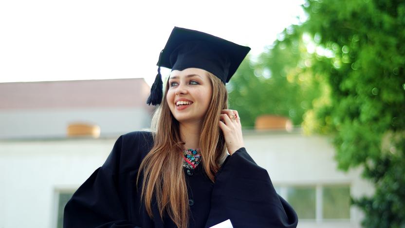 A beautiful graduate girl in the mantle keeps in hands graduate diploma and looks up.