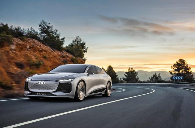 The new Audi A6 e-tron speeds along a cliff-side road with a sunset in the background.