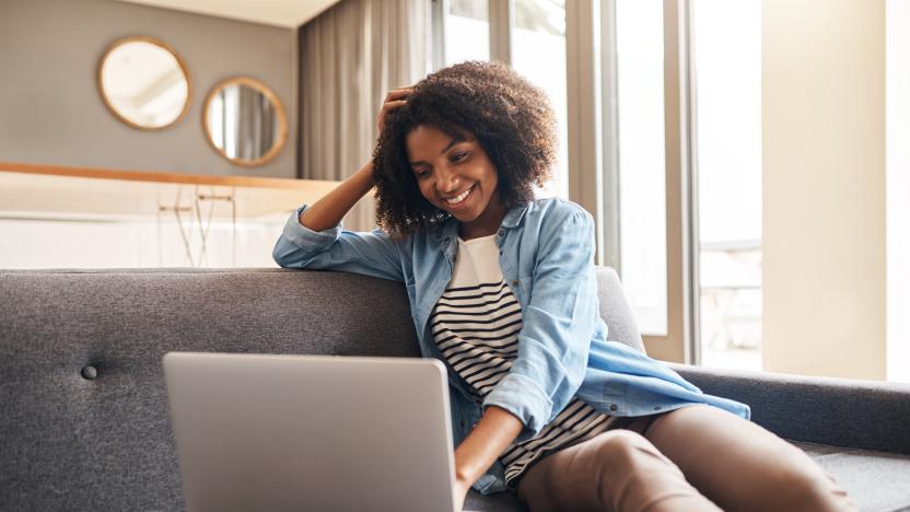 Shot of a young woman using her laptop while relaxing at home