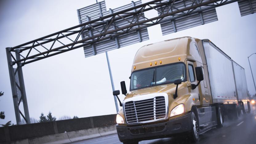 Brown modern big rig semi truck popular among drivers truckers going to long haul commercial cargo  driving on a wet road in the rain with headlights for safe driving and reflection of lights.