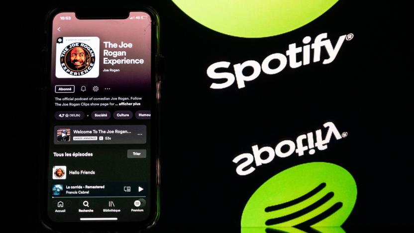 This picture taken in Toulouse, southwestern France, on January 31, 2022 shows a smartphone displaying the Joe Rogan podcast and a screen displaying the Spotify's logo. - Caught in a disinformation maelstrom, Spotify announces it will guide listeners of Covid-19 podcasts to established facts about the pandemic. This comes after artists pulled their songs in protest at the platform given on Spotify to podcaster Joe Rogan, accused of spreading damaging myths about the pandemic. (Photo by Lionel BONAVENTURE / AFP) (Photo by LIONEL BONAVENTURE/AFP via Getty Images)